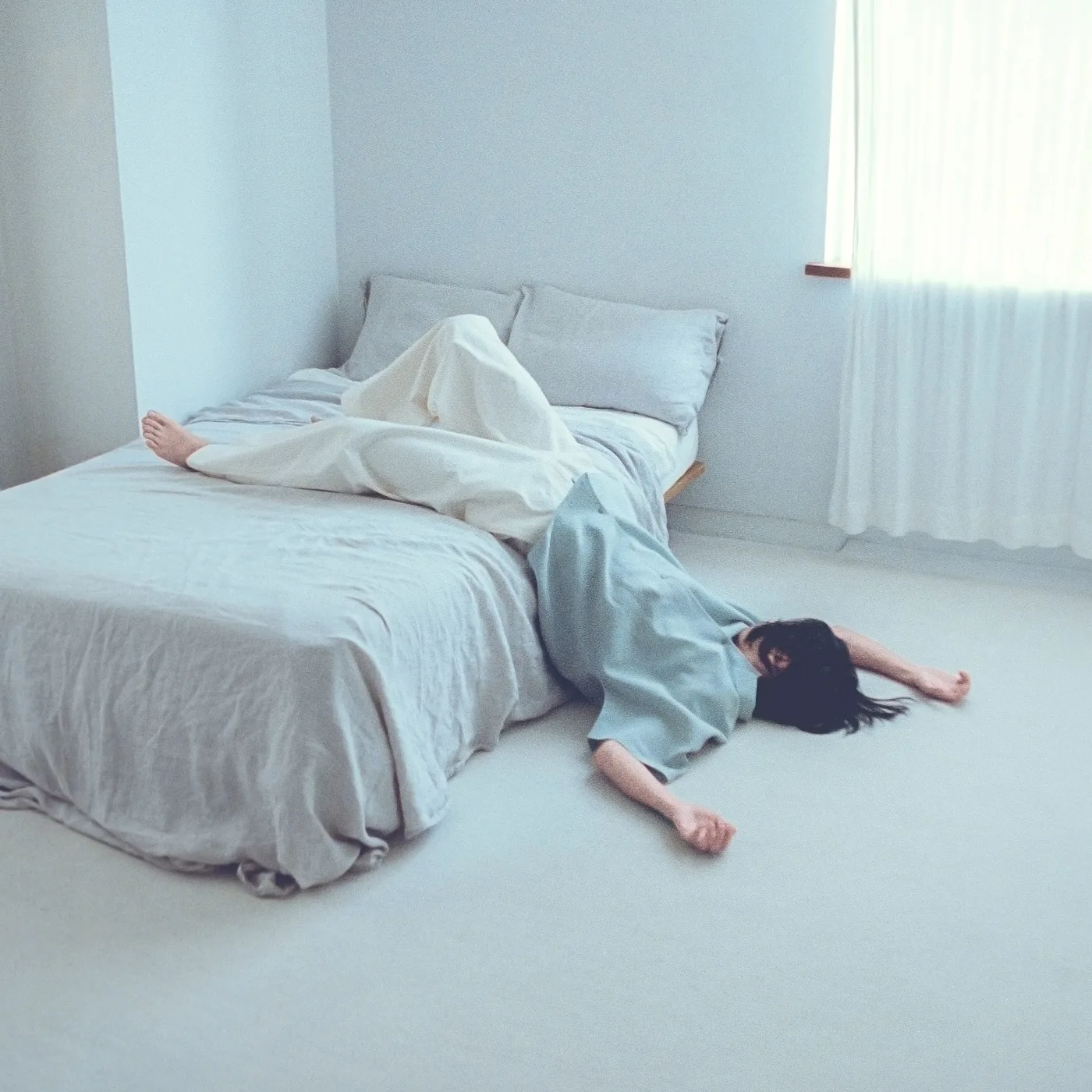 Portada de las nuevas canciones de Centimillimental: una persona cae de la cama al suelo en una habitación blanca