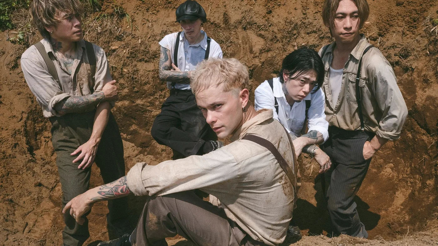 Foto promocional de coldrain para OPTIMIZE = OPTDEMISE: los cinco integrantes, con ropa manchada de tierra, posan dentro de una zanja