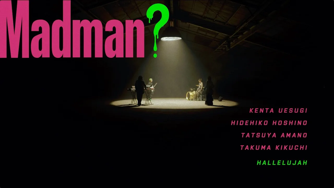 Imagen del video «Madman?» de LEADER: los cuatro músicos tocan bajo un reflector en una nave oscura, con el título en letras rosas y verdes