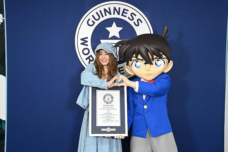Mai Kuraki sostiene el certificado de Guinness World Records junto a Conan Edogawa, frente al logotipo de Guinness
